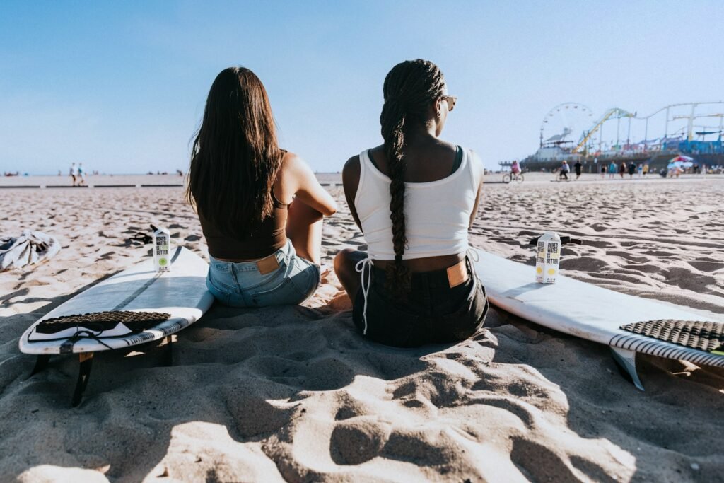 a couple of women sitting on top of a sandy beach